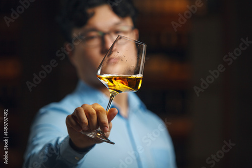 Sommelier Intently Evaluating Color and Transparency of White Wine in Glass