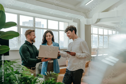 Colleagues discussing work on a laptop in a modern office