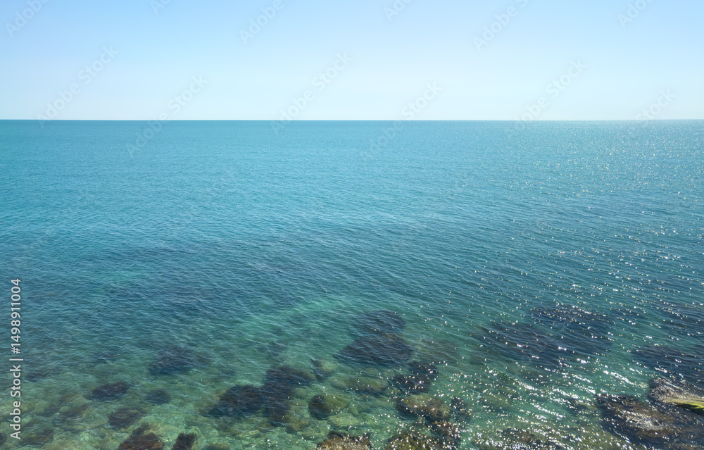 Fototapeta premium The ocean is calm and clear, with a few rocks visible in the water