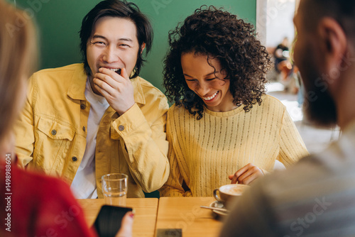 Diverse multinational group of friends laughing and talking at coffee shop table