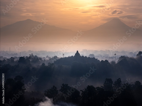 Fotografi Misty Borobudur temple in the morning with the Merapi, Merbabu and Arjuno mountain in the surroundings