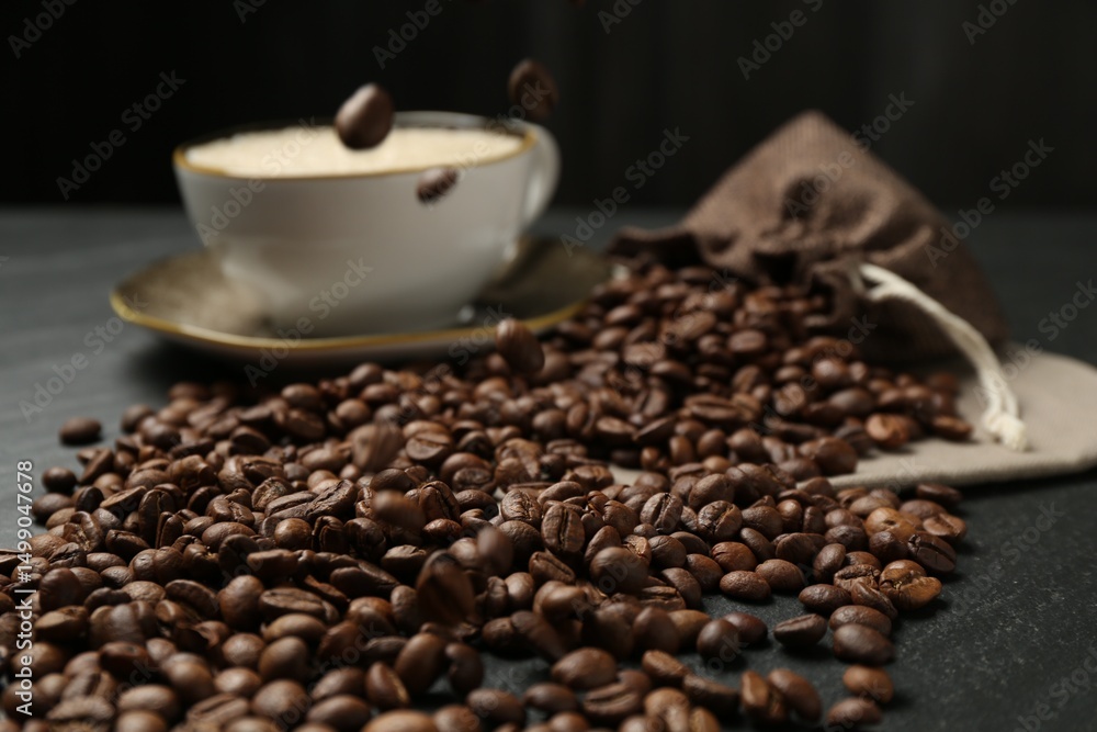 Fototapeta premium Aromatic coffee beans and hot drink on black table, closeup