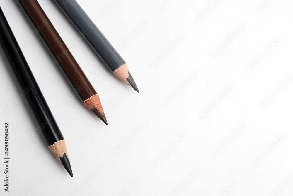 Three different eyebrow pencils on white background, top view. Space for text Three different eyebrow pencils on white background, top view. Space for text