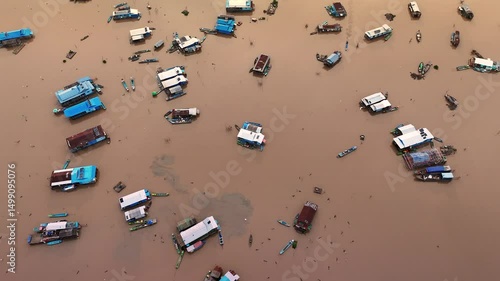 Top-down drone view of Tonle Sap’s floating village, Cambodia, with floating houses and boats scattered across the murky lake.