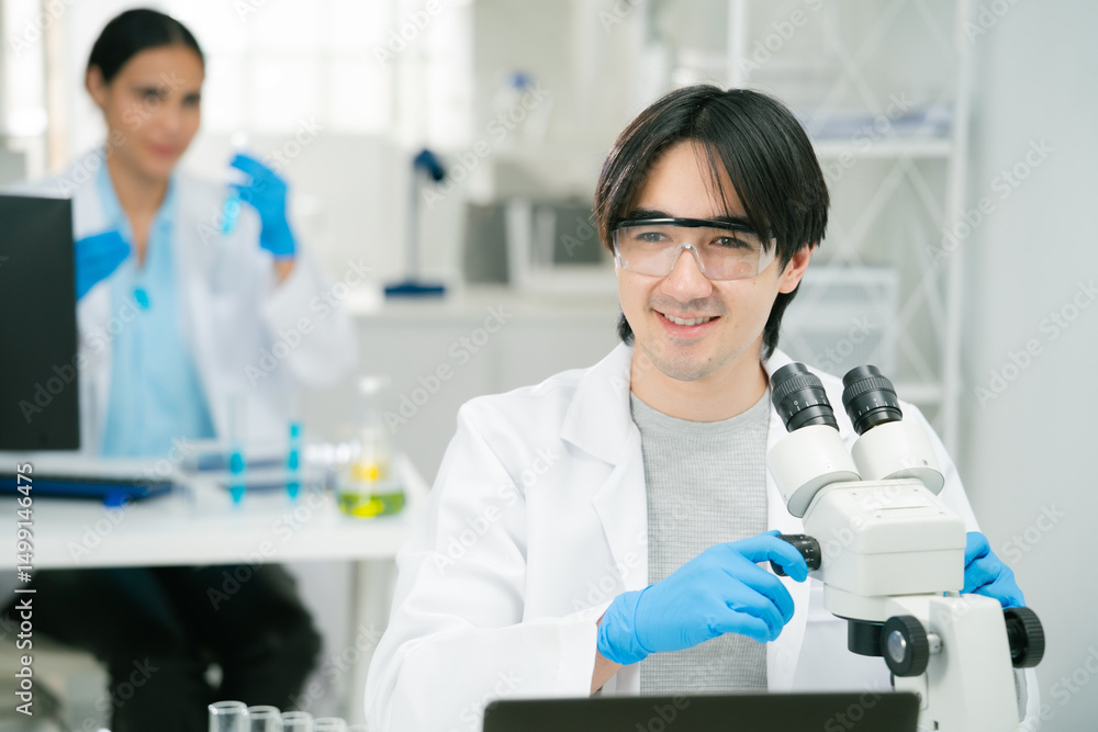 A scientist and researcher laboratory setting is using microscope while another scientist works with test tubes background, showcasing teamwork and focus. scientist researcher chemistry laboratory A scientist and researcher laboratory setting is using microscope while another scientist works with test tubes background, showcasing teamwork and focus. scientist researcher chemistry laboratory
