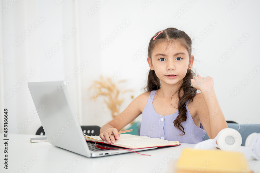 Asian kid or a girl looking away from laptop and raising a hand while sitting at white siting in the house Asian kid or a girl looking away from laptop and raising a hand while sitting at white siting in the house