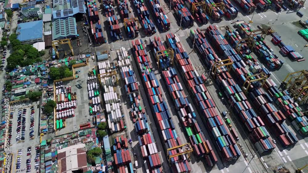 Aerial view of stacked cargo containers in the industrial port zone of Manila, Philippines, under bright daylight. Cranes, trucks, and vivid colors dominate the busy logistics hub. Aerial view of stacked cargo containers in the industrial port zone of Manila, Philippines, under bright daylight. Cranes, trucks, and vivid colors dominate the busy logistics hub.