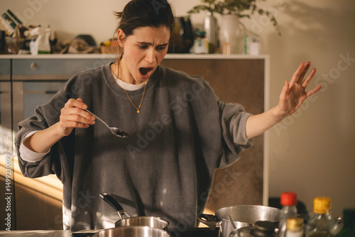 Young housewife having a calamity in the kitchen reacting in shock, she cooks dinner. Woman in a hurry, look sad and mad.