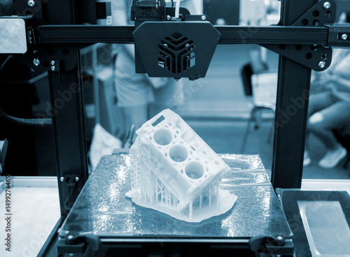 Prototype of car engine printed on 3D printer from molten white plastic on working surface 3D printer. Three-dimensional model. Additive modeling technology. Modern new printing industry. Blue color