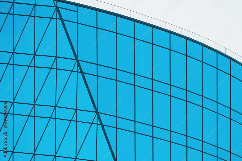 Fototapeta premium Modern architectural building showcasing curved glass facade in bright daylight with geometric pattern