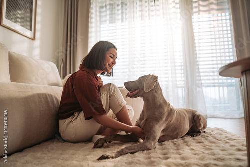 A woman enjoys joyful bonding with her dog in a warm, cozy living room