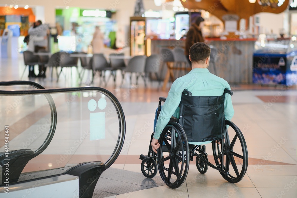 Obraz premium Customer using wheelchair looking at escalator in shopping mall