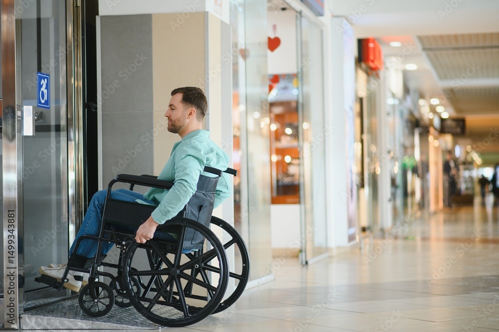 Obraz premium Person using wheelchair exiting elevator in shopping mall