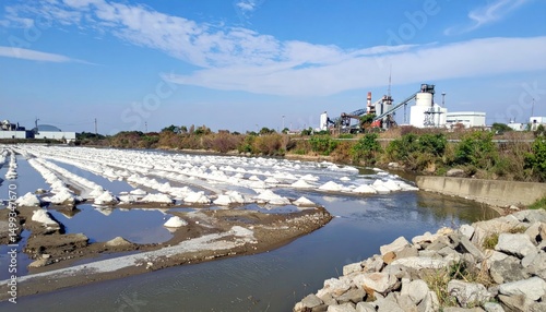 Salt fields panorama with reflecting pools, industrial structure against blue sky