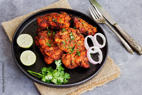Tandoori Chicken Thighs with Lemon, Onion  Garnished with Fresh Cilantro Close Up Photo

