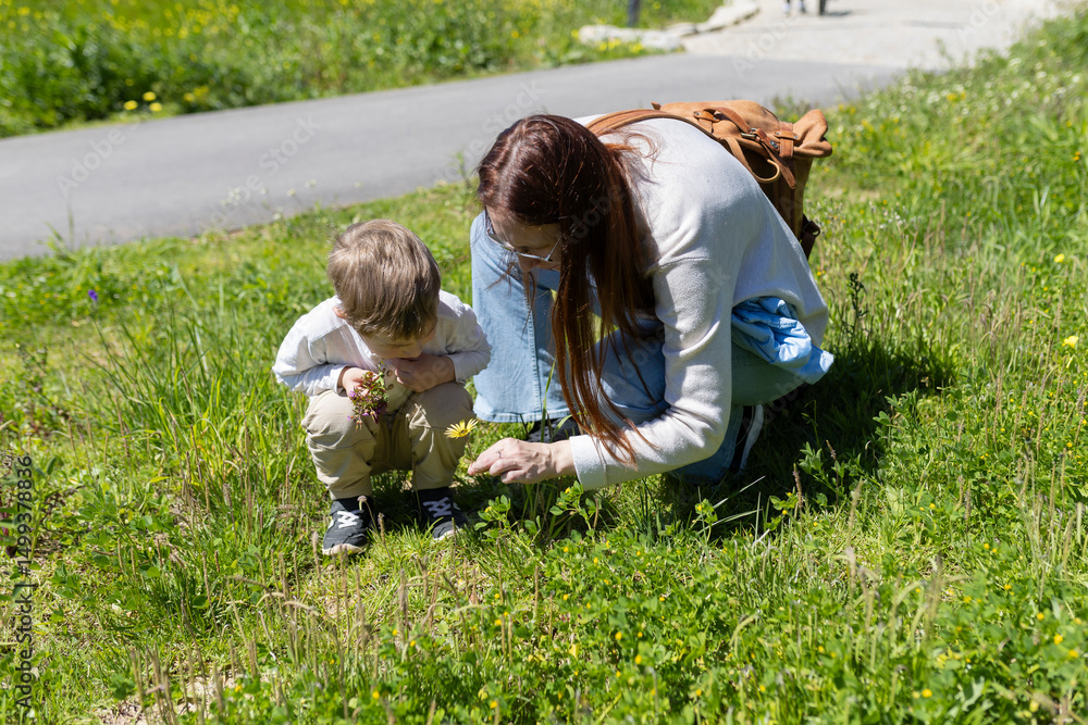 Fototapeta premium Mother and son discovering wildflowers in a meadow