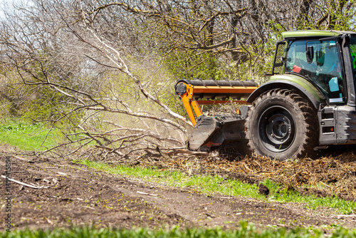 Picture of a tractor specialized in forest clearing that is in the process of destroying all the trees and bushes. Stop deforestation. Picture of a large tractor that destroys nature.