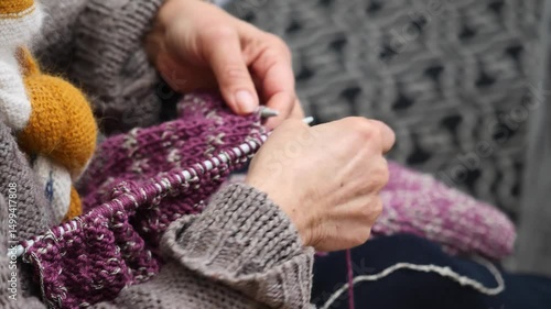 Woman is knitting a sweater. The sweater is purple and pink.