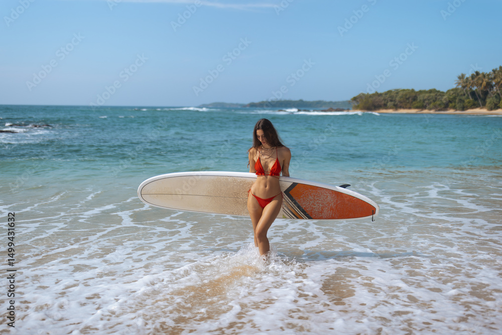 Woman in Red Bikini Walking with Surfboard on a Tropical Beach Woman in Red Bikini Walking with Surfboard on a Tropical Beach