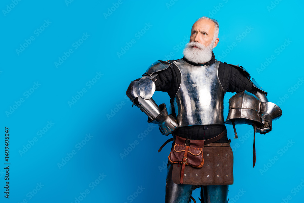 Naklejka premium Elderly bearded man wearing medieval-style metal armor posing against a blue background, representing historical themes and noble traits
