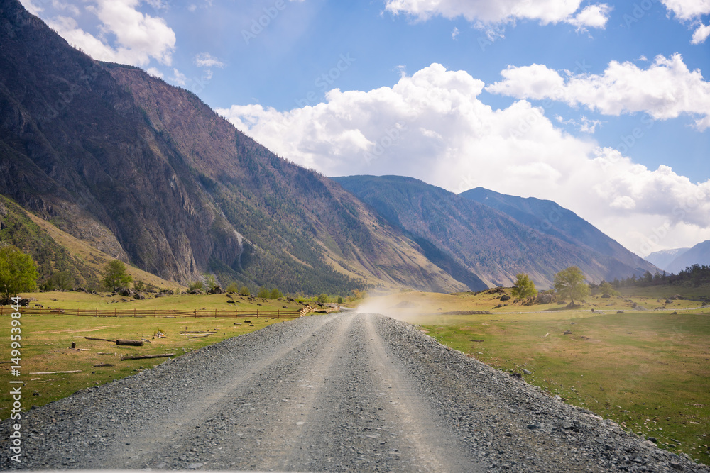 Fototapeta premium Dirt road running along Chulyshman river at entrance to Chulyshman valley in Altai Russia Scenic remote route through wild mountain landscape