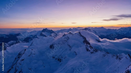 Snow-Covered Mountain Peaks at Twilight with Vibrant Sky and Rolling Clouds