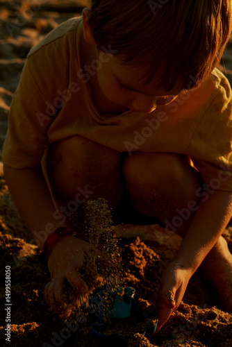 Little 3 year old boy is playing on the beach under the sun.