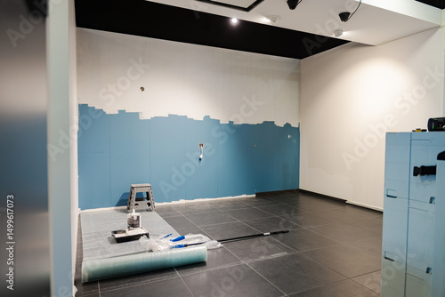 Mur bleu en cours de peinture blanche, capturant le contraste des couleurs et l'instant du changement.