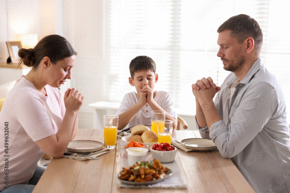 Fototapeta premium Family praying together before dinner at table indoors