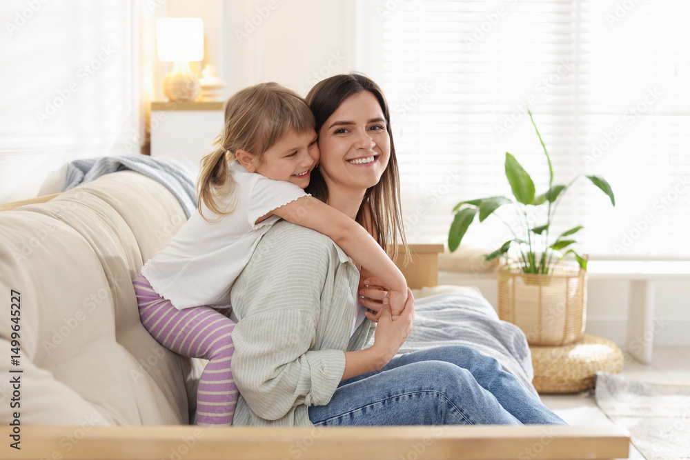 Obraz premium Happy mother and her cute daughter on sofa at home