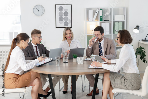 Coworkers working together at wooden table in office