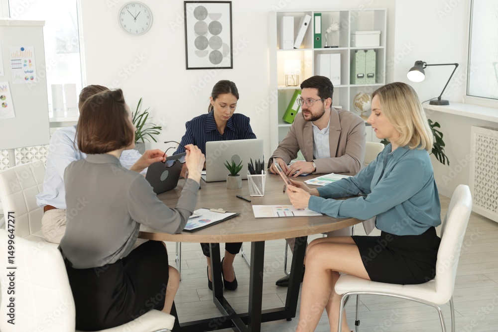 Coworkers working together at wooden table in office Coworkers working together at wooden table in office