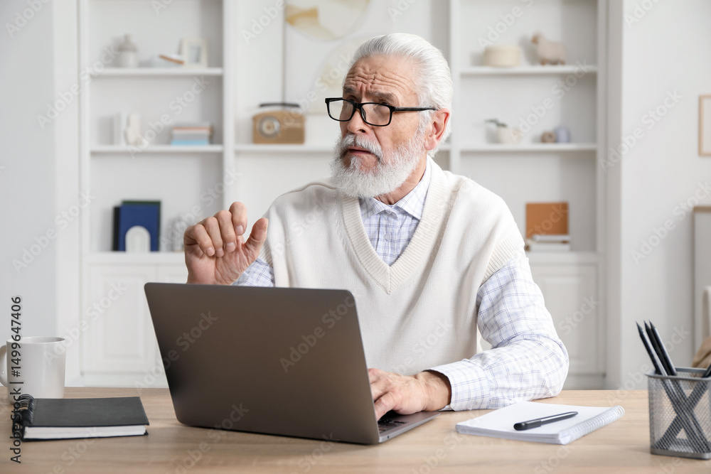 Senior man learning online using laptop at desk indoors. Self-study Senior man learning online using laptop at desk indoors. Self-study