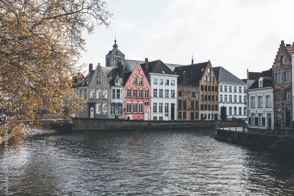 Obraz premium view of the old town of brugge in belgium, and its canals, on a spring day. pastel atmosphere and grey sky
