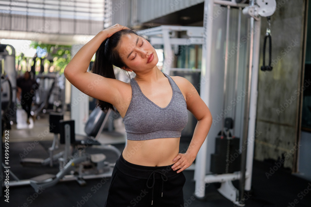 Fit young woman in sportswear stretching neck muscles before workout in a gym. Fit young woman in sportswear stretching neck muscles before workout in a gym.