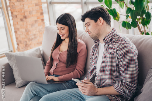 Young couple bonding at home while relaxing on the couch with a laptop, enjoying leisure time in a cozy living room setting.