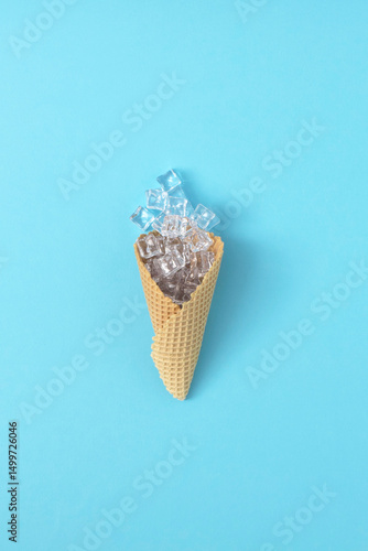 Ice cream cone with ice cubes on blue background. Minimal concept.