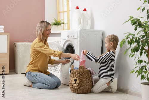 Fototapete Little girl and her mom doing laundry together at home