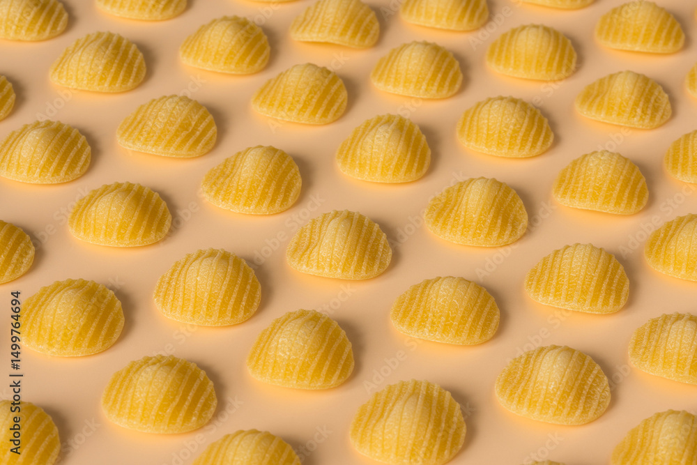 Fototapeta premium Background pasta , high-resolution . Top view of isolated a raw Italian durum wheat orecchiette pasta on a light orange background , flat lay .