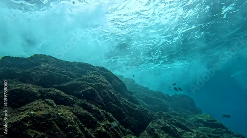 Underwater waves crashing onto the island rocks in Thailand. Scuba diving in the Andaman sea