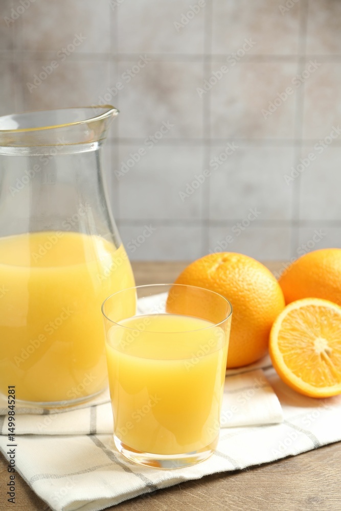 Fresh orange juice and fruits on wooden table against grey tiled wall, closeup Fresh orange juice and fruits on wooden table against grey tiled wall, closeup