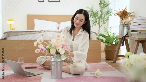 Asian smiling woman putting beautiful flowers on jar