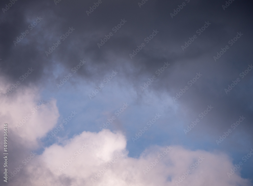 Dark and light clouds in the sky with soft blue showing through. A moody and natural weather scene, capturing a moment before or after rain. Dark and light clouds in the sky with soft blue showing through. A moody and natural weather scene, capturing a moment before or after rain.