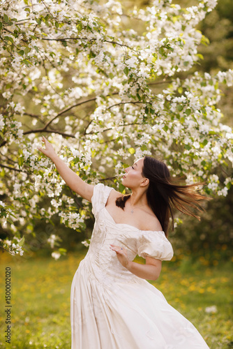 A girl in a dress and a blooming apple tree, taken at sunset