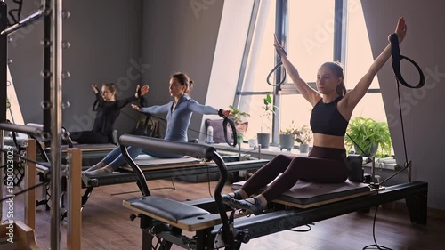 Woman training pilates on the reformer bed. Reformer pilates studio machine for fitness workouts in gym. Fit, healthy and strong authentical body. Fitness concept
