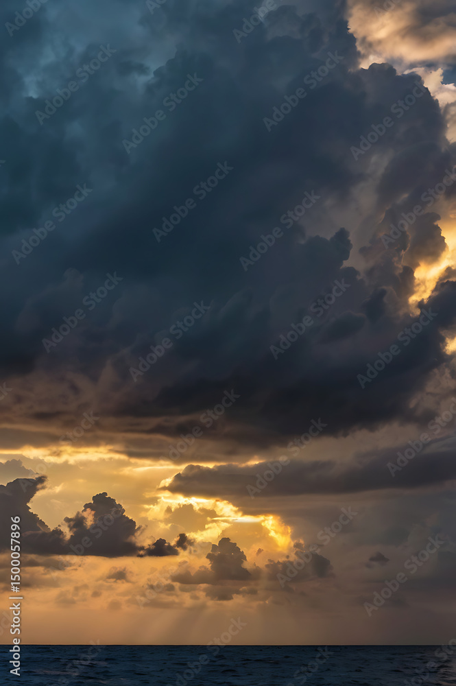 Fototapeta premium Dramatic Sunset Sky Over Ocean Golden Rays Pierce Dark Clouds