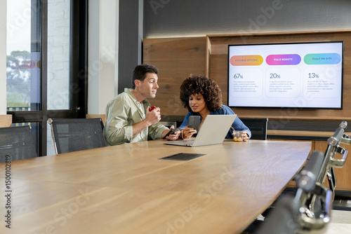 Diverse coworkers discussing flexible work options in conference room, with laptop and smartphones