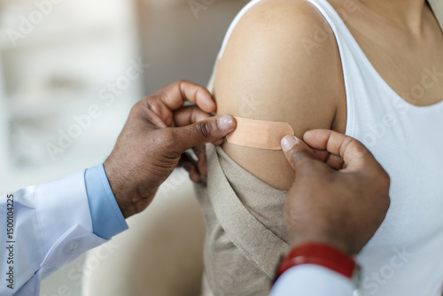 Tableau sur toile Doctor Applying Plaster On Arm Of Black Female Patient After Vaccine Shot, Close
