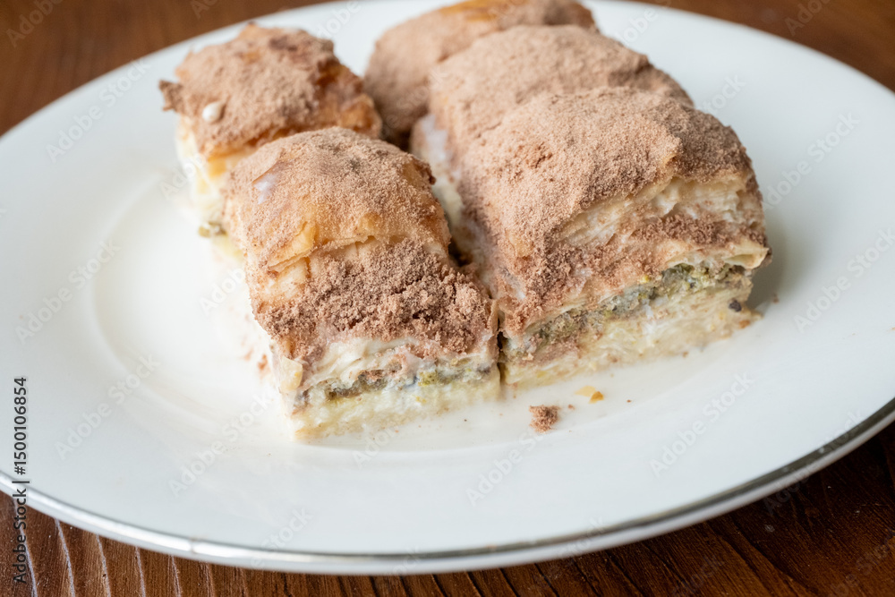 Cold baklava with cacao on a white plate close up Cold baklava with cacao on a white plate close up