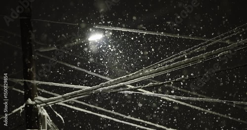 Beautiful nighttime scene showcasing snow gently falling against a backdrop of illuminated electric wires